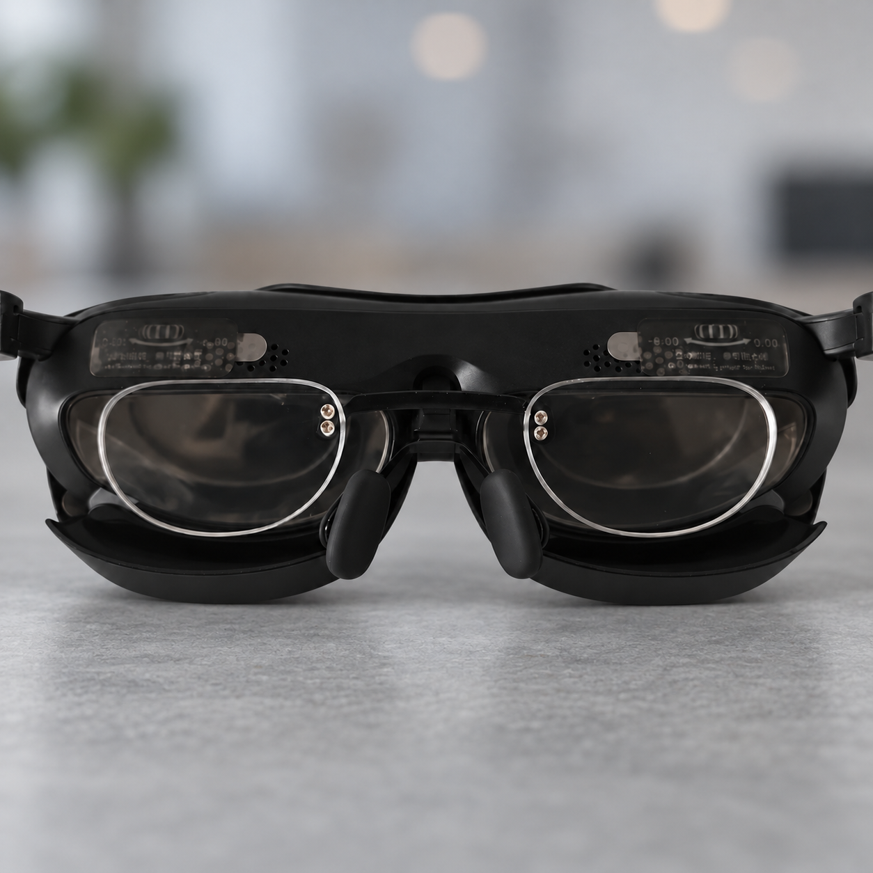 Clear inserts inside black Rokid glasses above the nose pads, against a cool-gray desk backdrop.