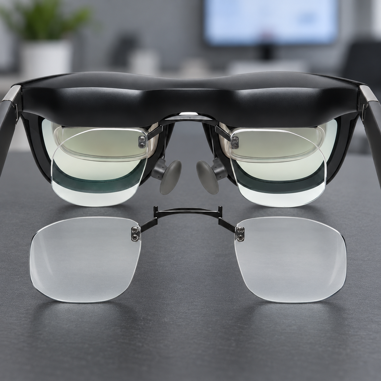 XREAL glasses with installed prescription inserts and a separate clear insert pair on a cool-gray desk.